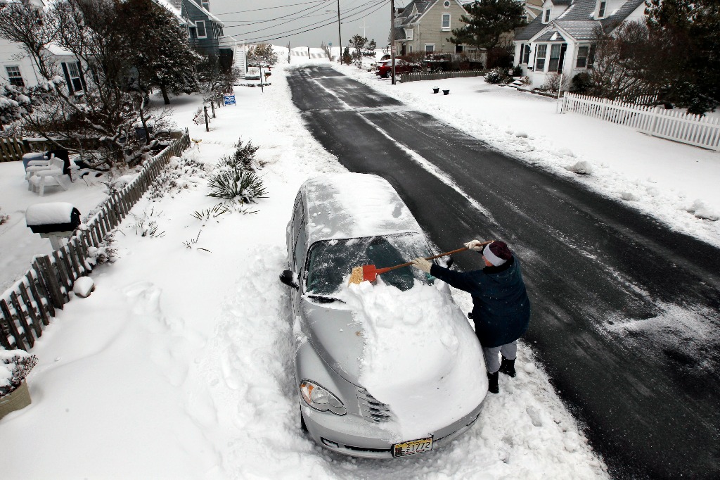 Una mujer limpia la nieve de su coche en Long Beach Township en Long Beach Island, Nueva Jersey. Foto Ap