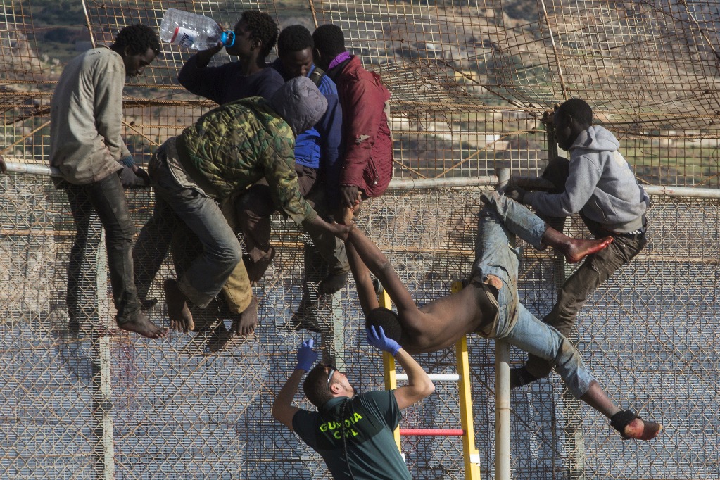 Un migrante subsahariano es ayudado por un agente de la Guardia Civil española después de que se desmayó en la parte superior de una valla metálica que divide a Marruecos y el enclave español de Melilla. Foto: AP