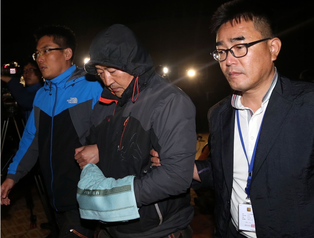 Autoridades sudcoreanas arrestaron al capitán del ferry (al centro) que naufragó frente a las costas de ese país con cientos de estudiantes a bordo. Foto Ap
