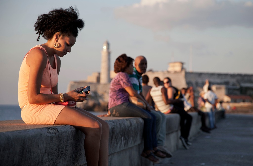 Una mujer usa un teléfono celular en el malecón de La Habana. Foto Ap