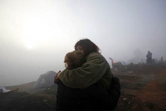 Unas mujeres se abrazan después de acampar junto a los restos de sus casas consumidas por los incendios forestales en Valparaíso. Foto Ap