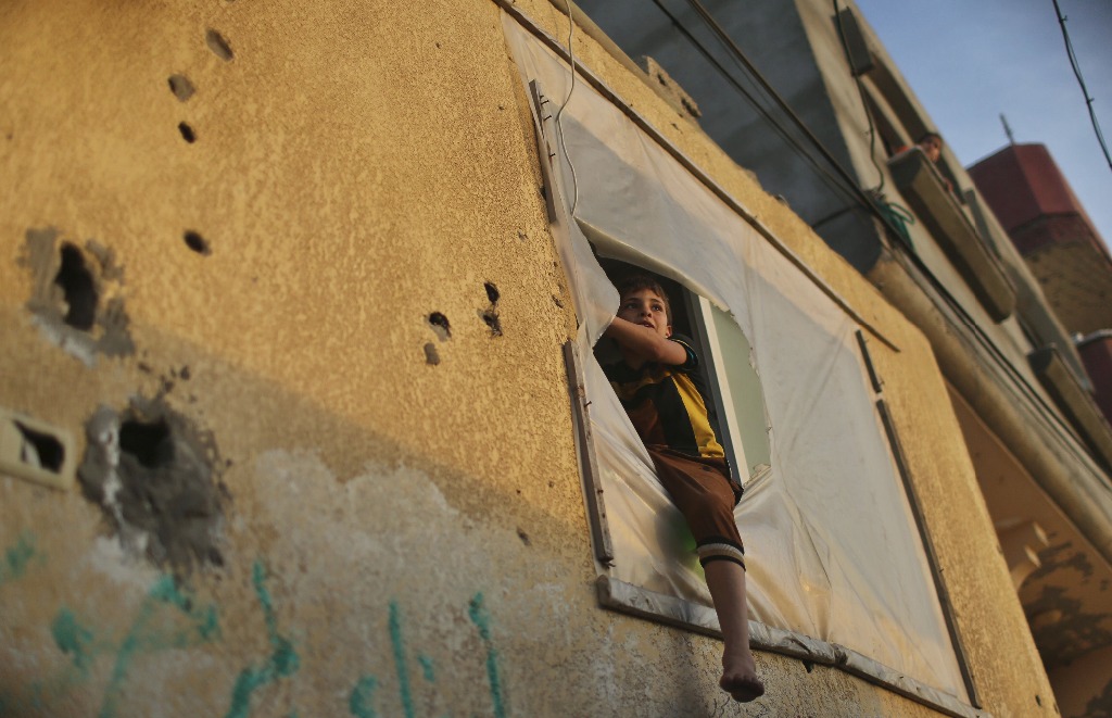 Un niño palestino mira a través de la ventana de su casa en el campamento de refugiados de Shati en la ciudad de Gaza. Foto Reuters