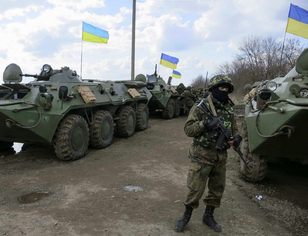 Un soldado ucraniano vigila cerca de blindados de transporte de personal en un puesto de control cerca de la ciudad de Izium. Foto Reuters