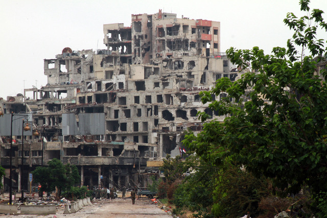 Militares permanecen frente a edificios dañados después de la evacuación del miércoles de los combatientes de la oposición, en la antigua ciudad de Homs, al centro de Siria. Foto Xinhua