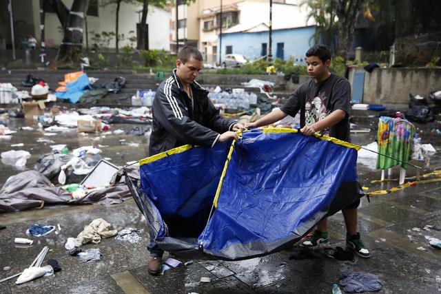 Dos hombres intentan reconstruir un campamento desmantelado por la Guardia Nacional venezolana este jueves en el distrito de Chacao. Foto Reuters