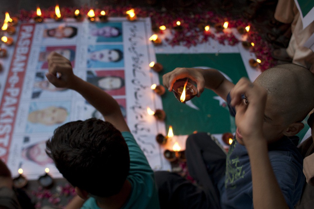 Familiares de las personas que fallecieron en un ataque en el aeropuerto de Karachi encendieron velas en honor a las víctimas. Foto Ap