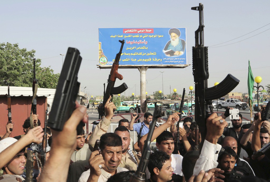Combatientes tribales chiítas iraquíes levantan sus armas y corean consignas contra el Isil en Ciudad Sadr, este miércoles. Foto Ap