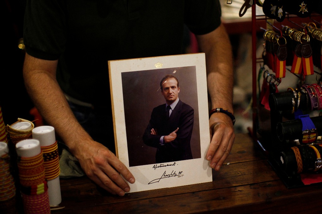 Un vendedor muestra una fotografía del rey Juan Carlos autografiada por el monarca. Foto Reuters