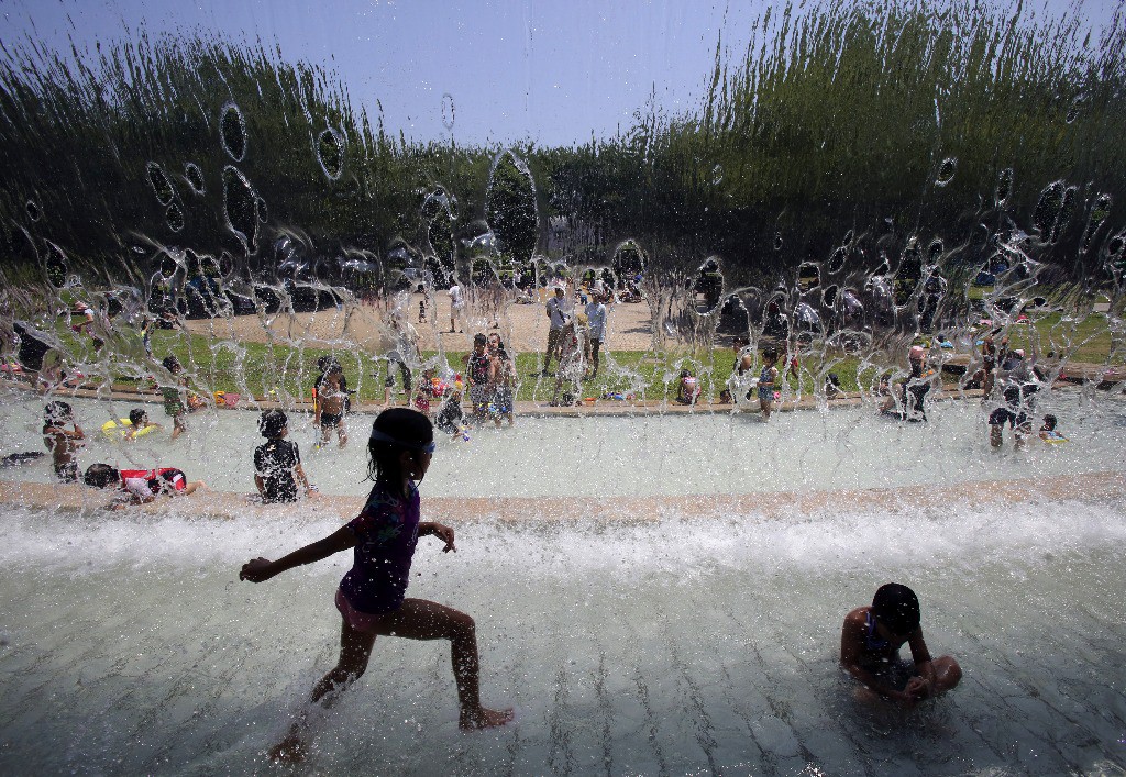 Niños juegan con el agua en una fuente en Tokio ante las altas temperaturas. Foto Ap