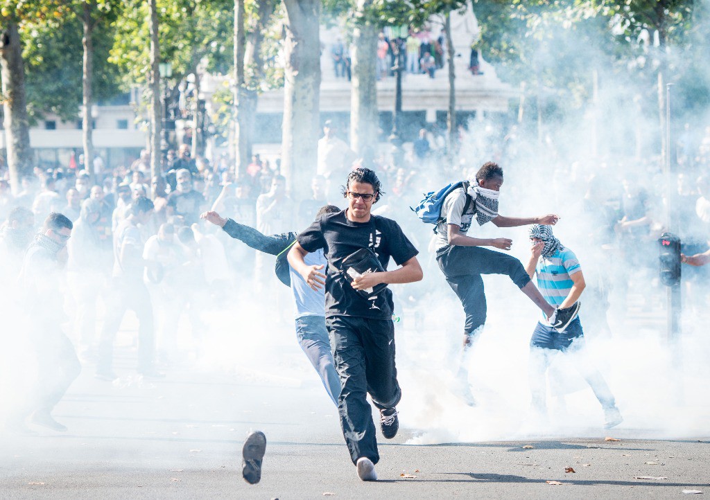 Manifestantes tratan de escapar de los gases lacrimógenos en la Plaza de la República. Foto Ap