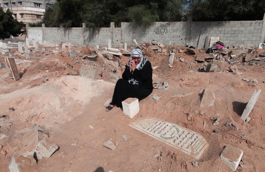 Una mujer palestina ora sobre la tumba de un familiar en el cementerio durante la celebración del Eid al-Fitr. Foto: Xinhua