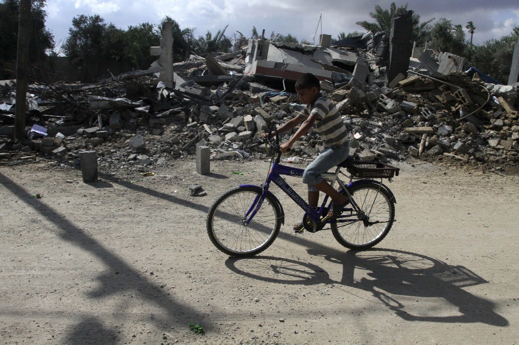 Un niño palestino conduce una bicicleta frente a un edificio destruido por un ataque aéreo israelí, este martes. Foto Xinhua