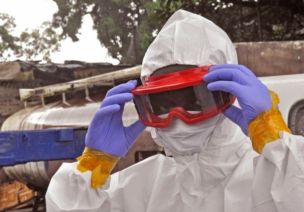 Un trabajador de salud de Liberia prepara su traje protector antes de tener contacto con un cadáver víctima de ébola. Foto Ap
