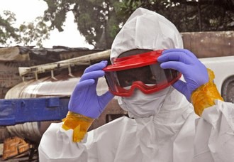 Un trabajador de salud de Liberia prepara su traje protector antes de tener contacto con un cadáver víctima de ébola. Foto Ap