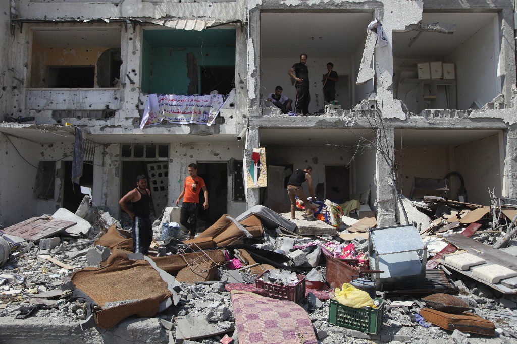 Palestinos recogen pertenencias de sus viviendas destruidas después de ser alcanzadas por un ataque israelí, en la villa de Khuzaa, Gaza. Foto Xinhua