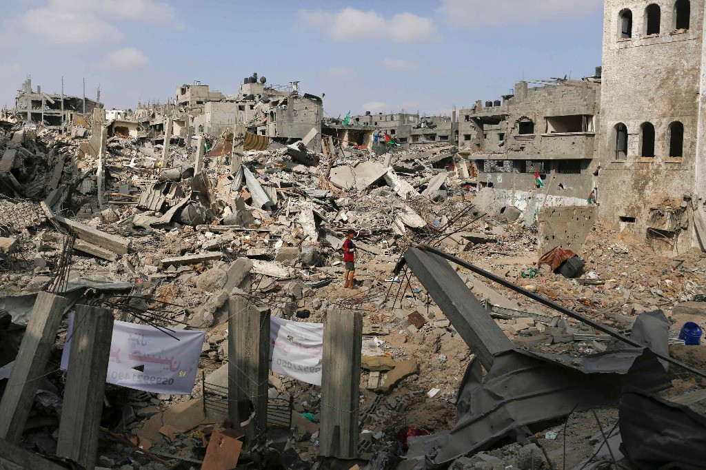 Un niño observa este martes las ruinas de los edificios destruidos por bombardeos israelíes. Foto Reuters