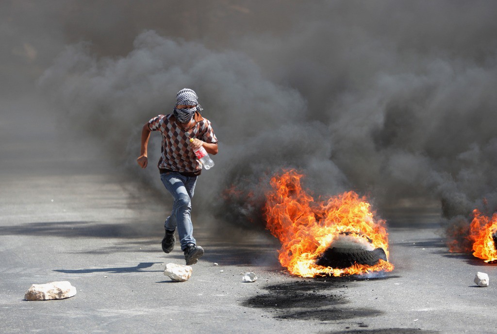 Un palestino huye de soldados israelíes durante los enfrentamientos registrados este viernes en la franja de Gaza. Foto Ap