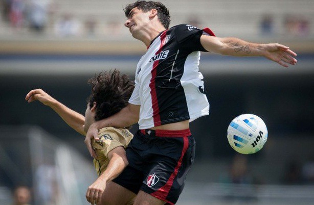 Matías Britos, de Pumas, disputa el balón con Facundo Erpen de Atlas, durante el partido de este domingo en el Estadio Olímpico Universitario. Foto Xinhua