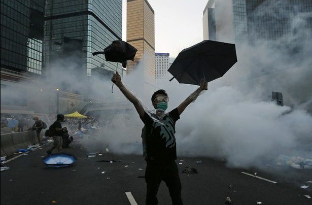 Un manifestante se protege con su paraguas del gas lacrimógeno lanzado por la policía para dispersar la protesta en la calle principal del distrito financiero central de Hong Kong. Foto Reuters