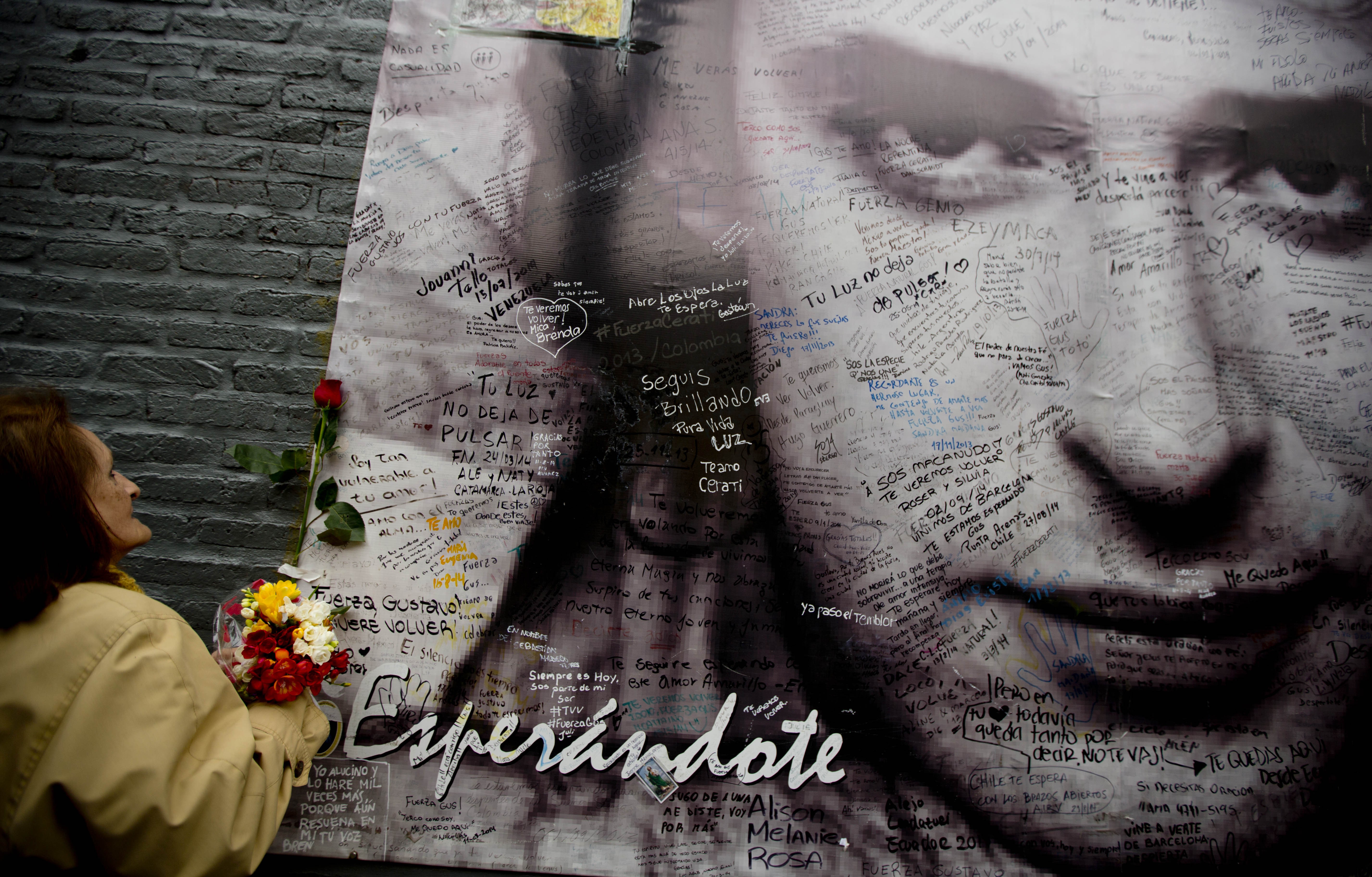 Una mujer coloca flores sobre un poster con la imagen de Gustavo Cerati frente a la clínica donde falleció en Buenos Aires. Foto Ap