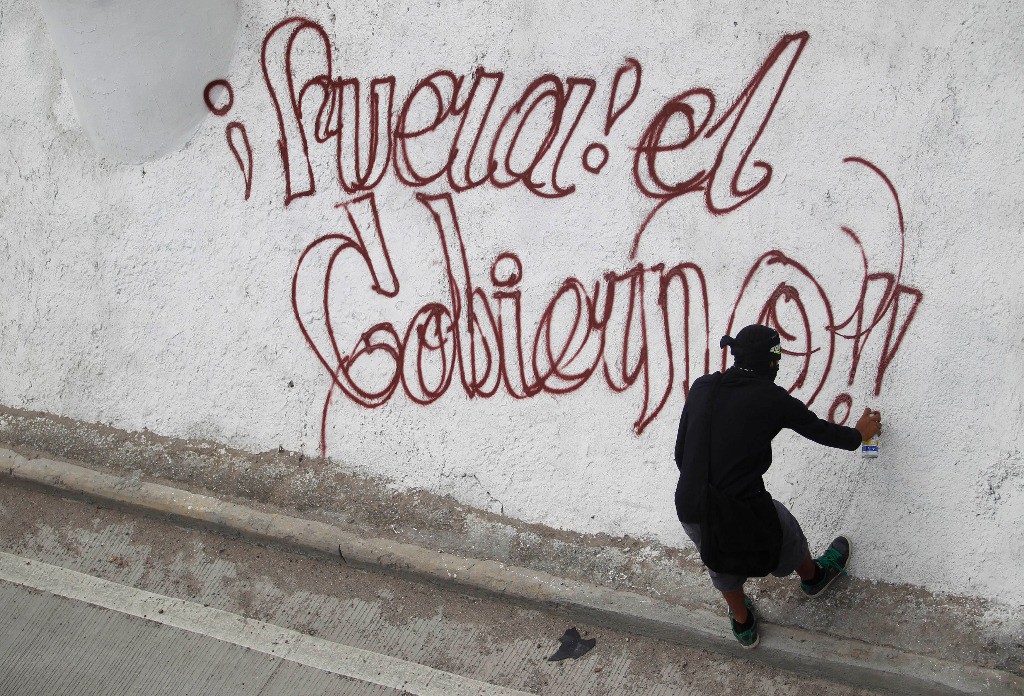 Un activista pinta una consigna contra el gobierno de Guerrero durante una manifestación ayer en Chilpancingo para exigir la aparición de 43 estudiantes desaparecidos. Foto Reuters