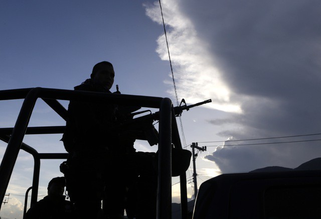 Policías federales montan guardia en una carretera cercana a las fosas clandestinas halladas en Pueblo Viejo, en las afueras de Iguala. Foto Reuters