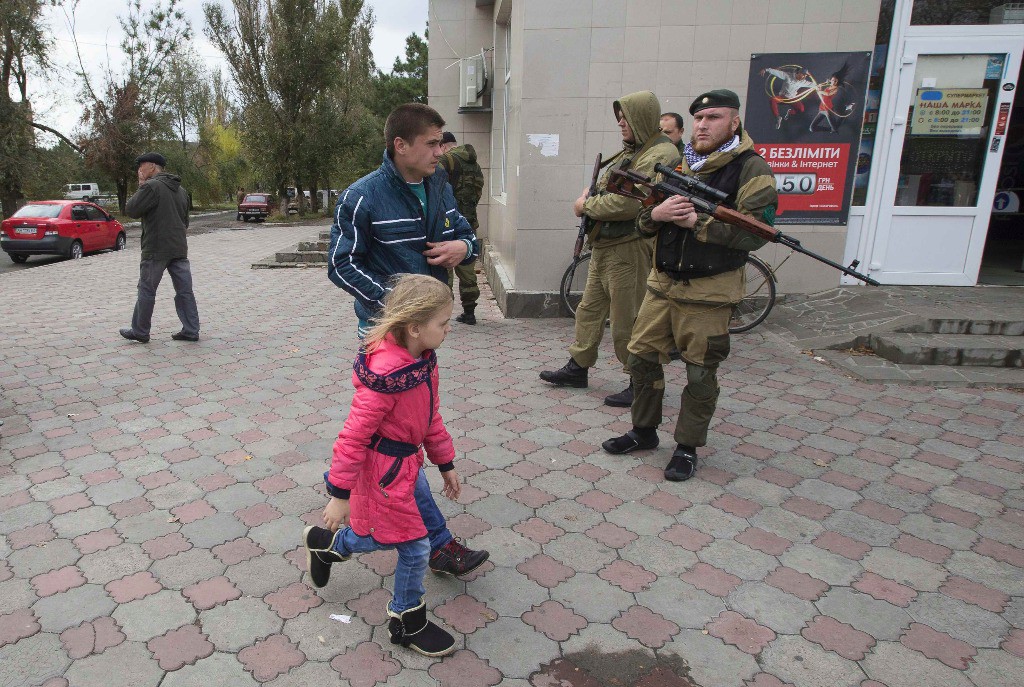 Residentes pasan junto a pro rusos en la ciudad de Novoazovsk, Ucrania. Foto Reuters