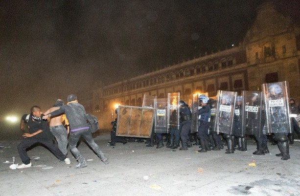 Un enfrentamiento se suscitó ayer en el Zócalo, luego que un grupo de personas trataron de quitar las vallas que resguardaban Palacio Nacional y arrojó objetos contra policías. Foto Pablo Ramos