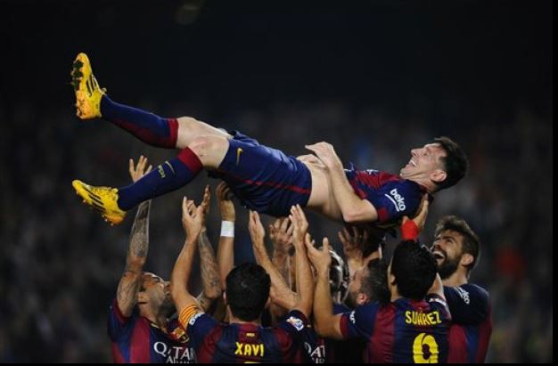 Lionel Messi es levantado por sus compañeros después de anotar contra el Sevilla, en la Liga española de futbol, en el estadio Camp Nou, en Barcelona. Foto AP