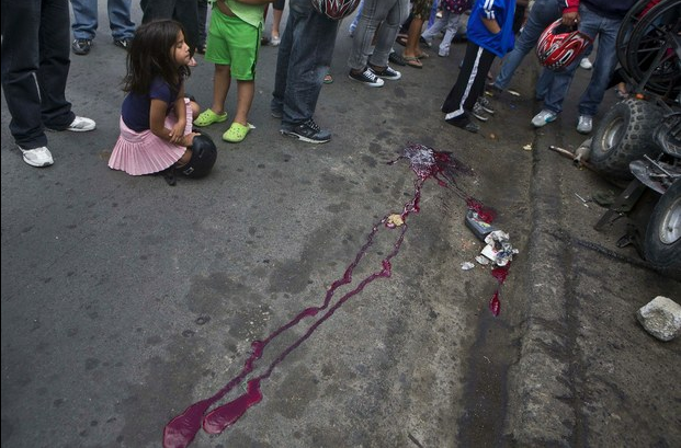 Una niña observa el sitio donde fue asesinada una persona en Tegucigalpa, Honduras, el 01 de diciembre de 2014. Foto Ap