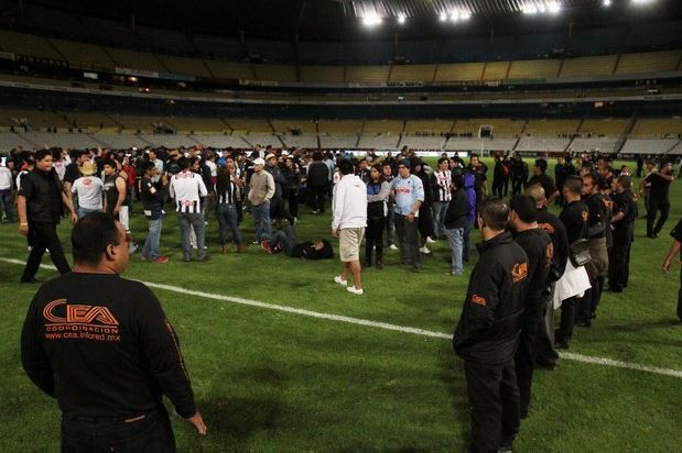 Elementos de seguridad del estadio Jalisco resguardó a los seguidores del equipo Monterrey en el terreno de juego. Foto Cuartoscuro/Archivo