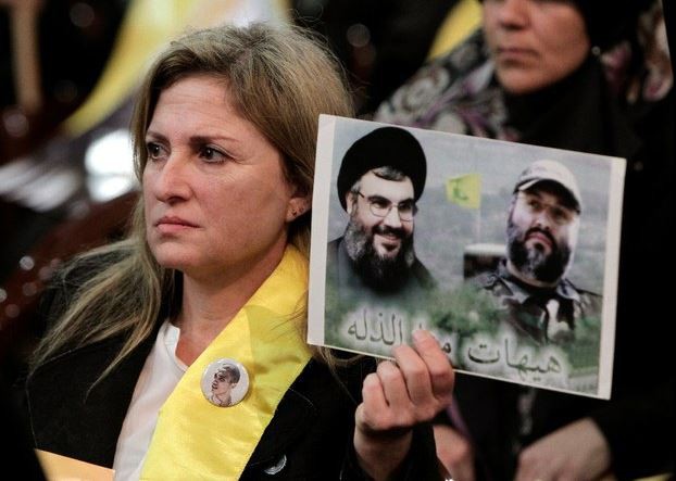 Una mujer sostiene una imagen del comandante militar de Hezbollah, Imad Mughniyeh (derecha), el 30 de enero de 2015. Foto Ap
