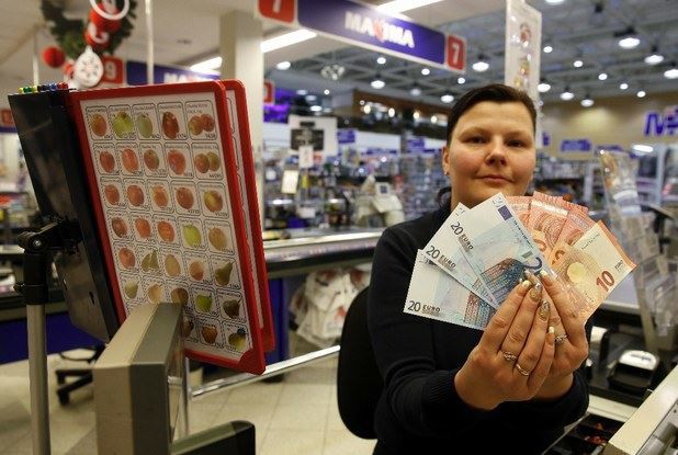 Una vendedora en un supermercado de Lituania muestra los billetes de euro, este jueves. Foto Ap