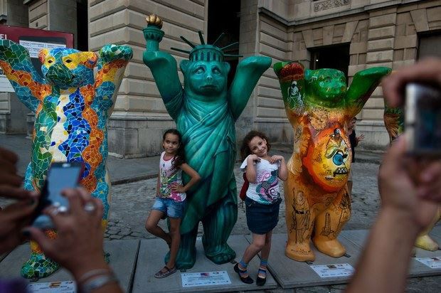 Niñas posan con la escultura de un oso que representa a Estados Unidos, durante la exhibición 'United Buddy Bears', en La Habana. La exposición, con alrededor de 140 objetos, representa la cultura de varios países. Foto Xinhua