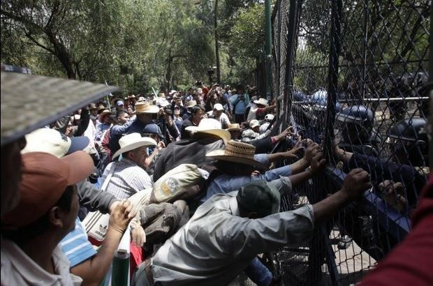 Campesinos que marchan hacia Los Pinos buscan tirar vallas dispuestas por granaderos, a la altura de Chivatito. Foto: La Jornada