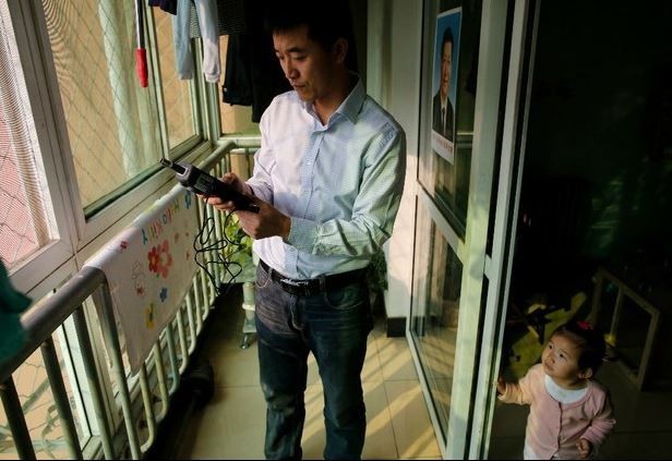 Liu Ruiqiang mide la calidad del aire con su contador de partículas en un balcón en su casa, mientras su hija lo observa, en Pekín, el 3 de febrero de 2015. Foto Reuters