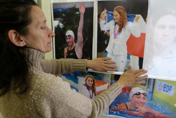 Una mujer clava retratos de la nadadora francesa Camille Muffat en su club de natación en Niza, quien murió en un accidente de helicóptero al filmar un reality show. Foto Ap