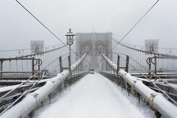 Un trabajador limpia la nieve en el puente de Brooklyn en Nueva York. Foto Reuters