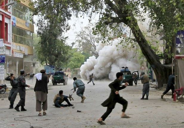 Afganos corren para esconderse tras el atentado suicida frente a un banco en Jalalabad, que dejó al menos 33 muertos y más de 100 heridos. Foto Reuters