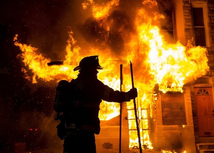 Bomberos de la ciudad de Baltimore trabajan en una casa que fue incendiada durante los disturbios. Foto Reuters