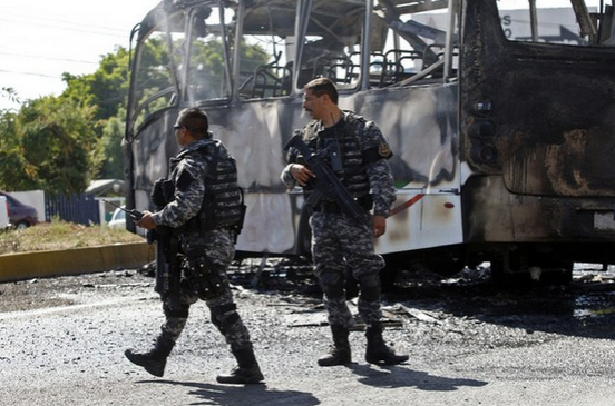 Policías estatales de Jalisco custodian un autobús que fue incendiado por la delincuencia organizada y utilizado como barricada en Guadalajara, el pasado 1 de mayo. Foto Ap