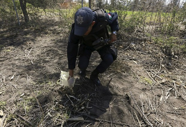 Un policía recolecta evidencia en el rancho El Sol, donde ocurrió el enfrentamiento que dejó 42 civiles y un municipal muertos el pasado 22 de mayo. Foto Reuters