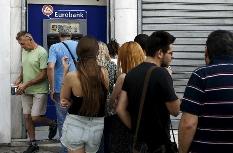 Personas hacen fila para retirar dinero de un cajero automático de Eurobank en Atenas. Foto Reuters