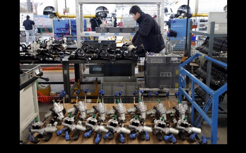 Un obrero en la línea de ensamble de una fábrica de vehículos electrónicos, en Pekín. Foto Reuters