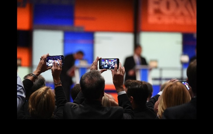 Personas toman fotos a los candidatos republicanos en un debate organizado por la cadena Fox. Foto Ap