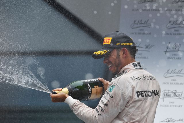 El piloto británico, Lewis Hamilton, en el tradicional festejo con champagne en el podio de ganadores. Foto Afp