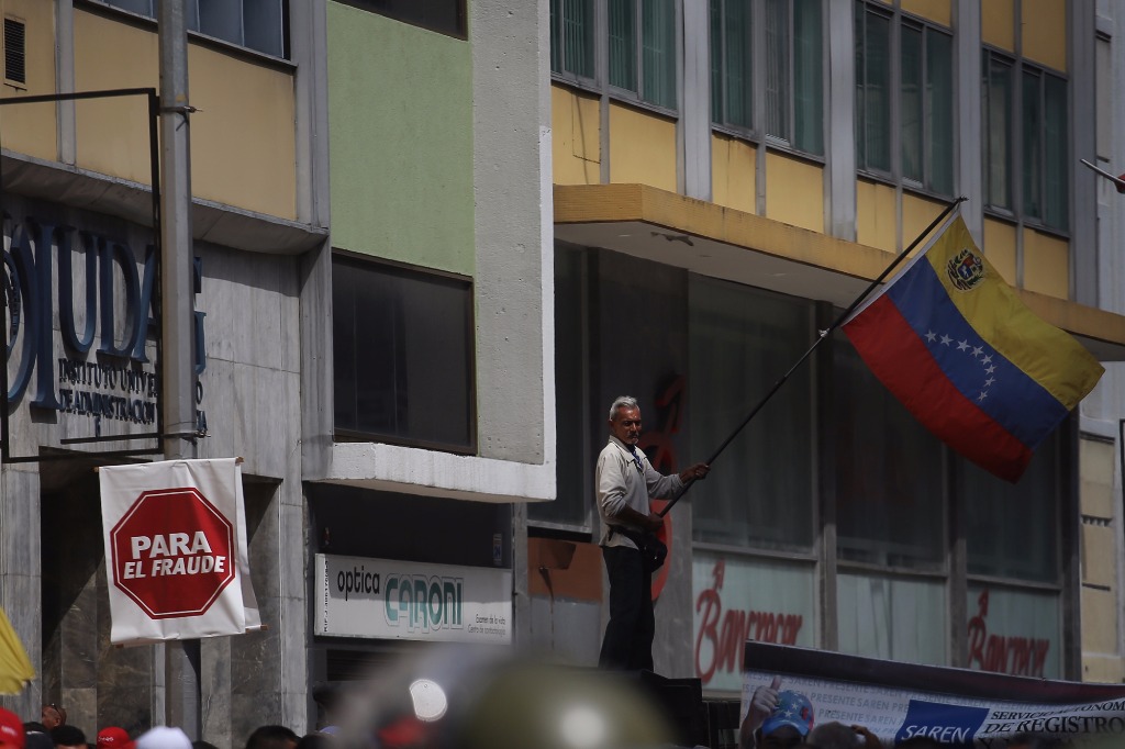 Simpatizante del gobierno de Maduro ondea una bandera de Venezuela. Foto Xinhua